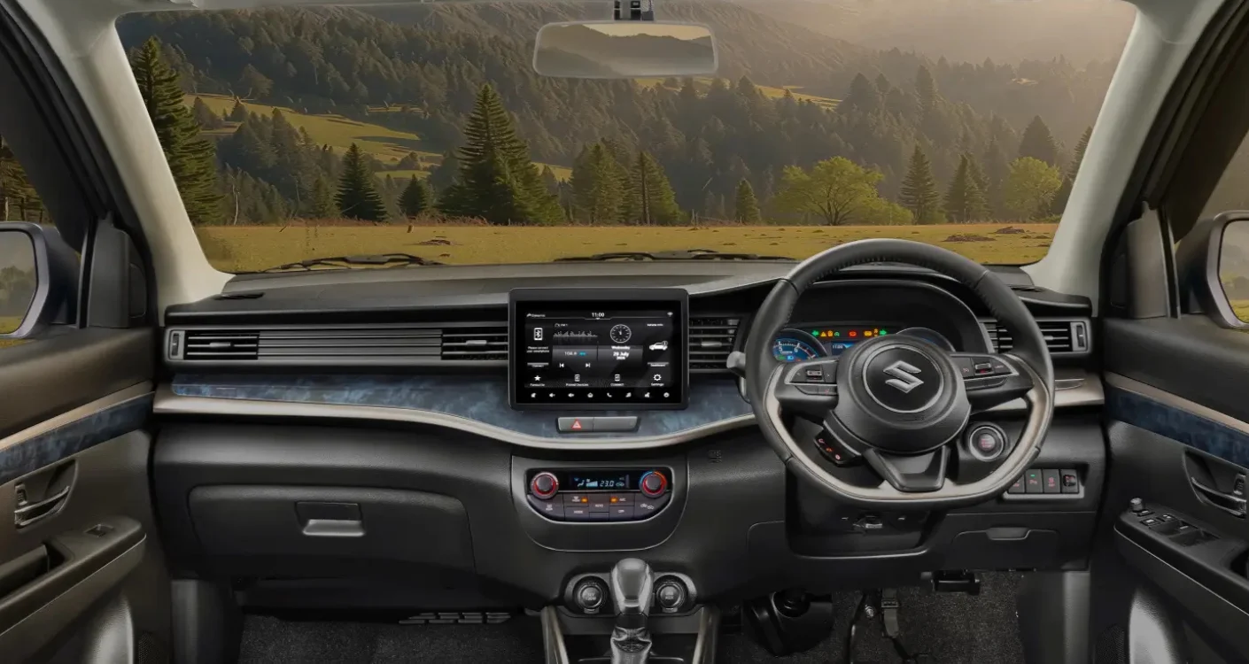 Interior mobil Suzuki modern dengan dashboard hitam, layar infotainment besar, setir multi-fungsi, dan pemandangan alam perbukitan hijau, ideal untuk perjalanan di sekitar Kota Batam.